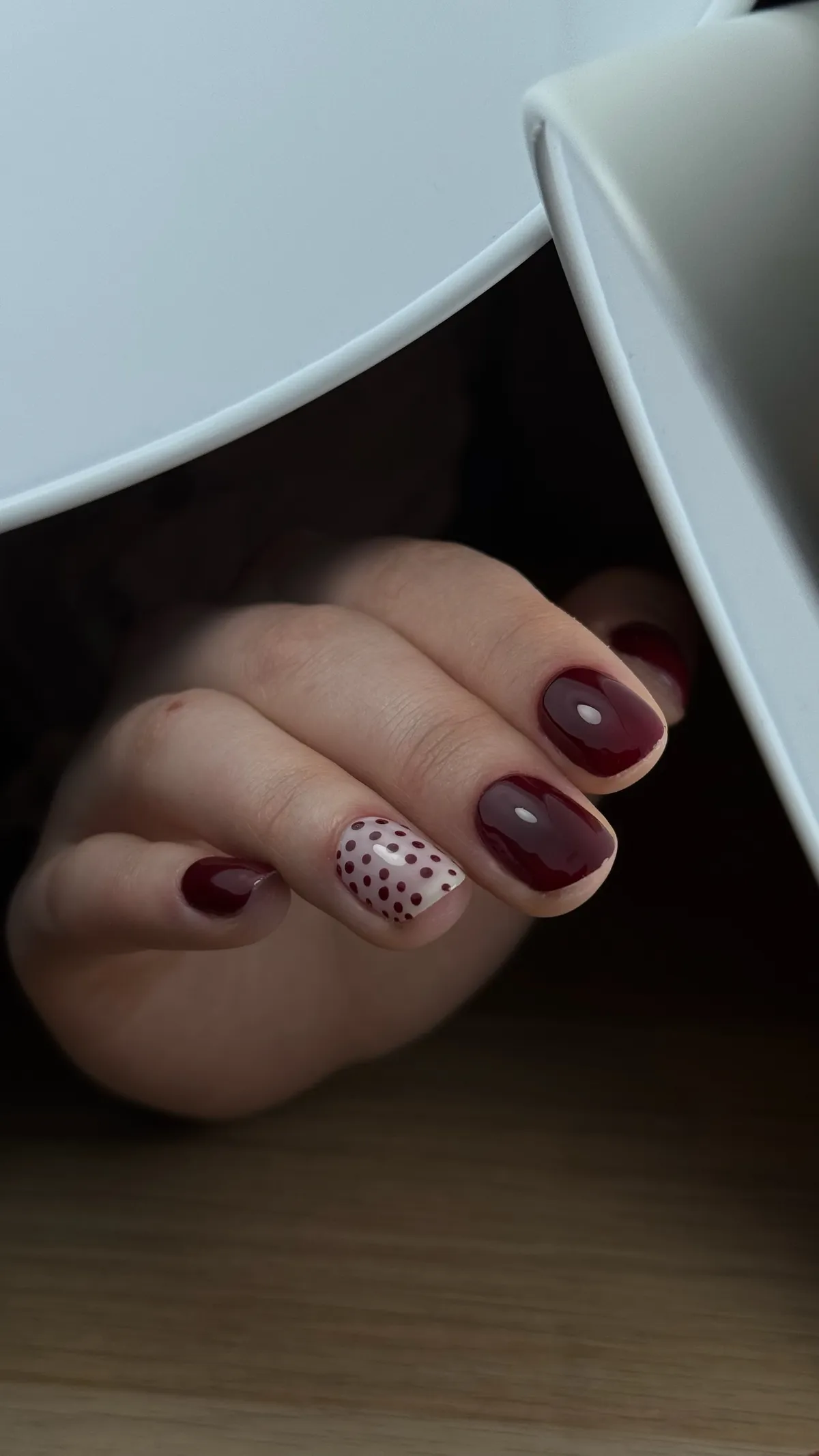Vernis bordeaux brillant avec accent pois sur base nude